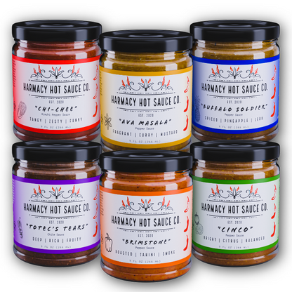 Six jars of Harmacy Hot Sauce Co. hot sauces with colorful labels on a white background