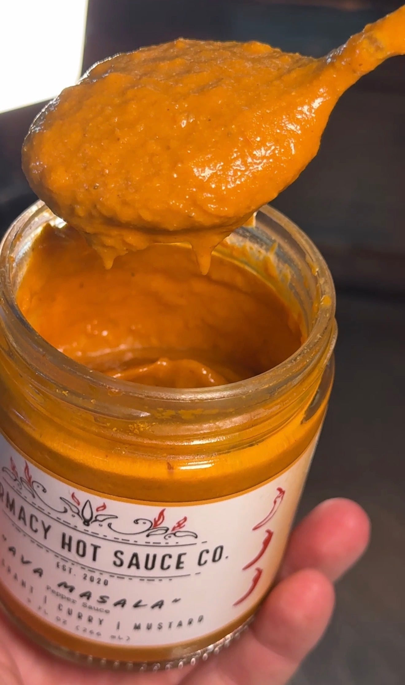 Jar of hot sauce with a spoonful being lifted, showing the brand 'Harmacy Hot Sauce Co.'
