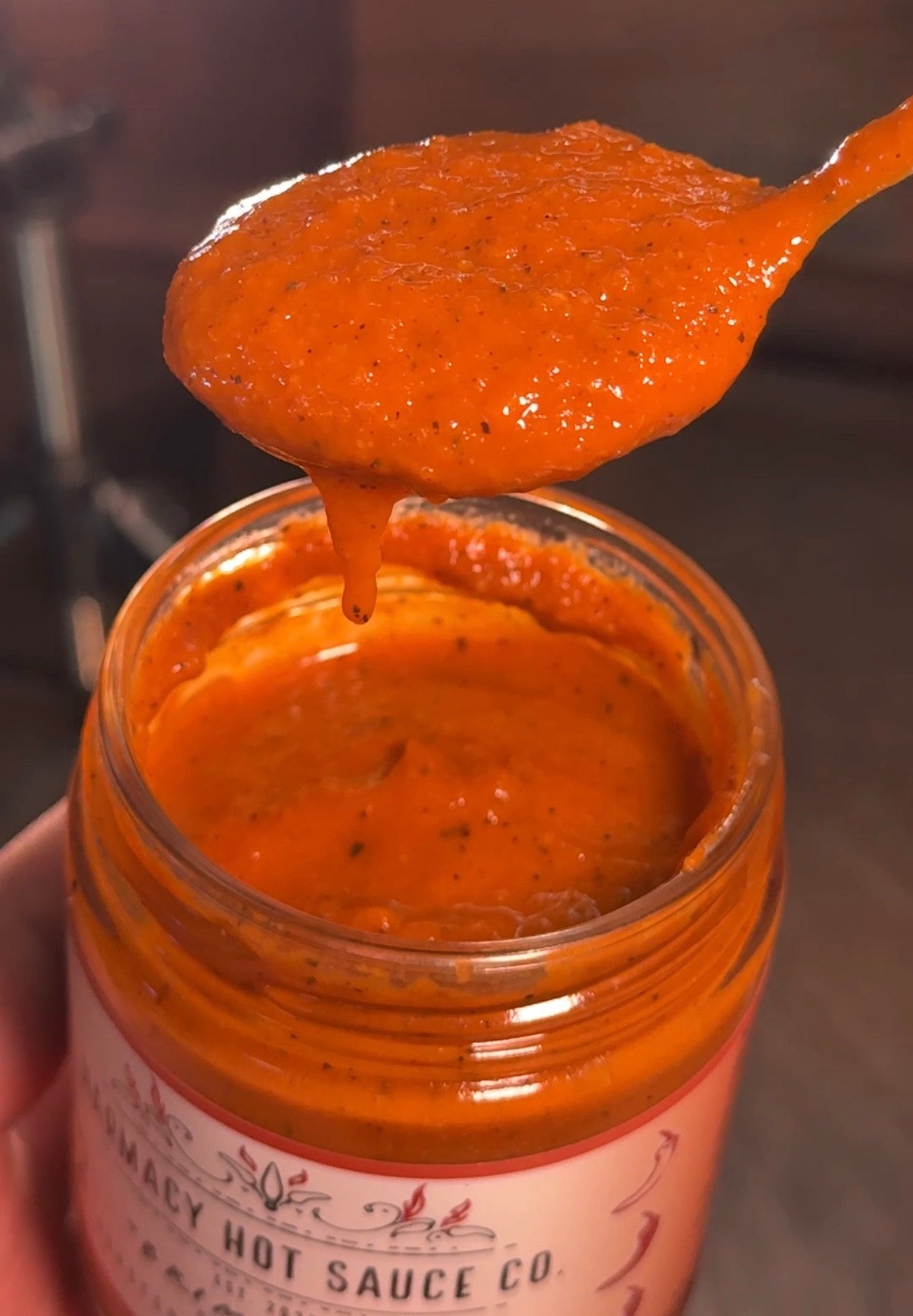 Jar of hot sauce with a spoonful being lifted, showing the brand 'Harmacy Hot Sauce Co.'