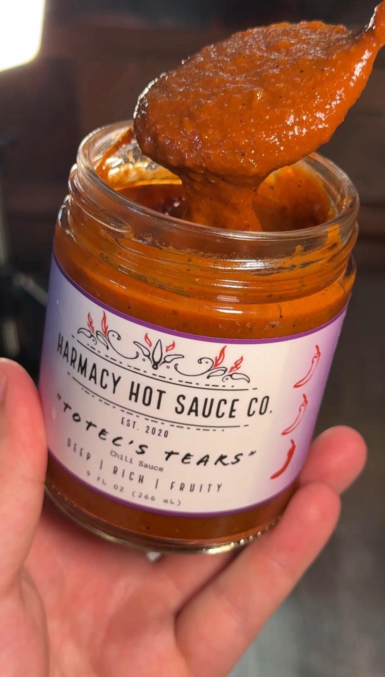 Jar of hot sauce with a spoonful being lifted, showing the brand 'Harmacy Hot Sauce Co.'